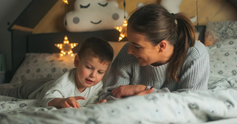 Mom reading to preschooler in bed. Struggling with preschool sleep problems? Discover how to help your 3-5 year old fall asleep easier and sleep through the night.