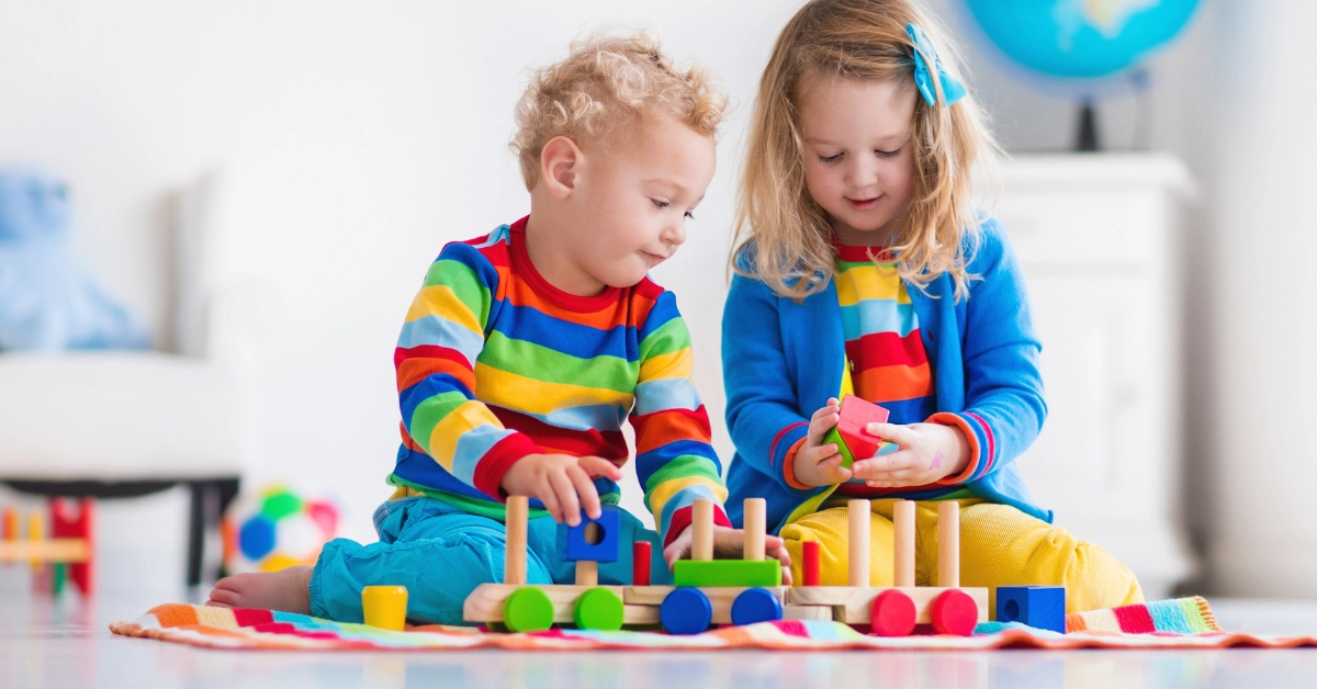 Two young children playing with colorful toy train - "I've Been Working On The Railroad" sing-along for Pre-K kids, building language skills, rhythm, and coordination through musical fun.