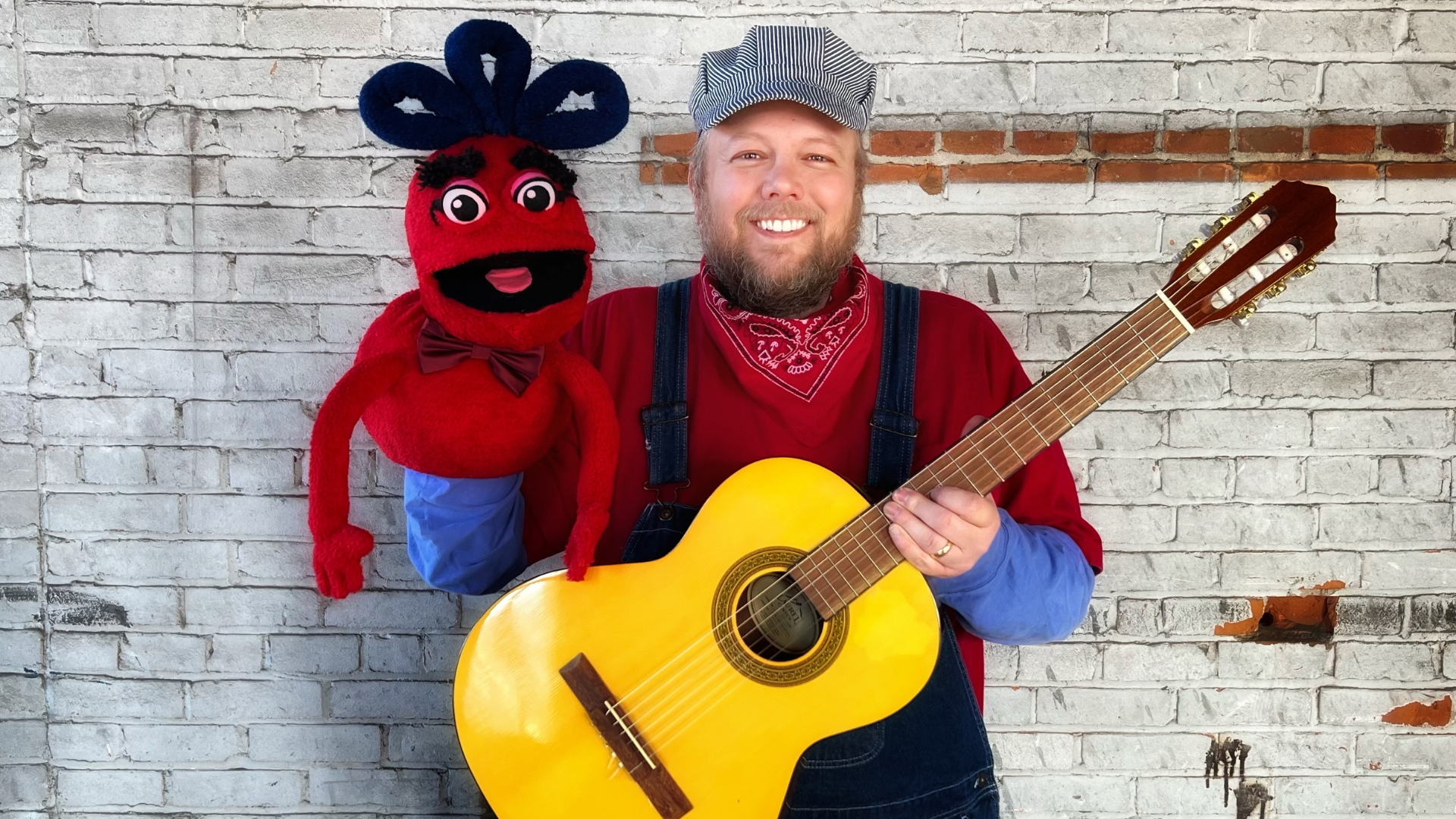 Conductor Jack holds a guitar and his puppet friend Naybob from the Zinghoppers