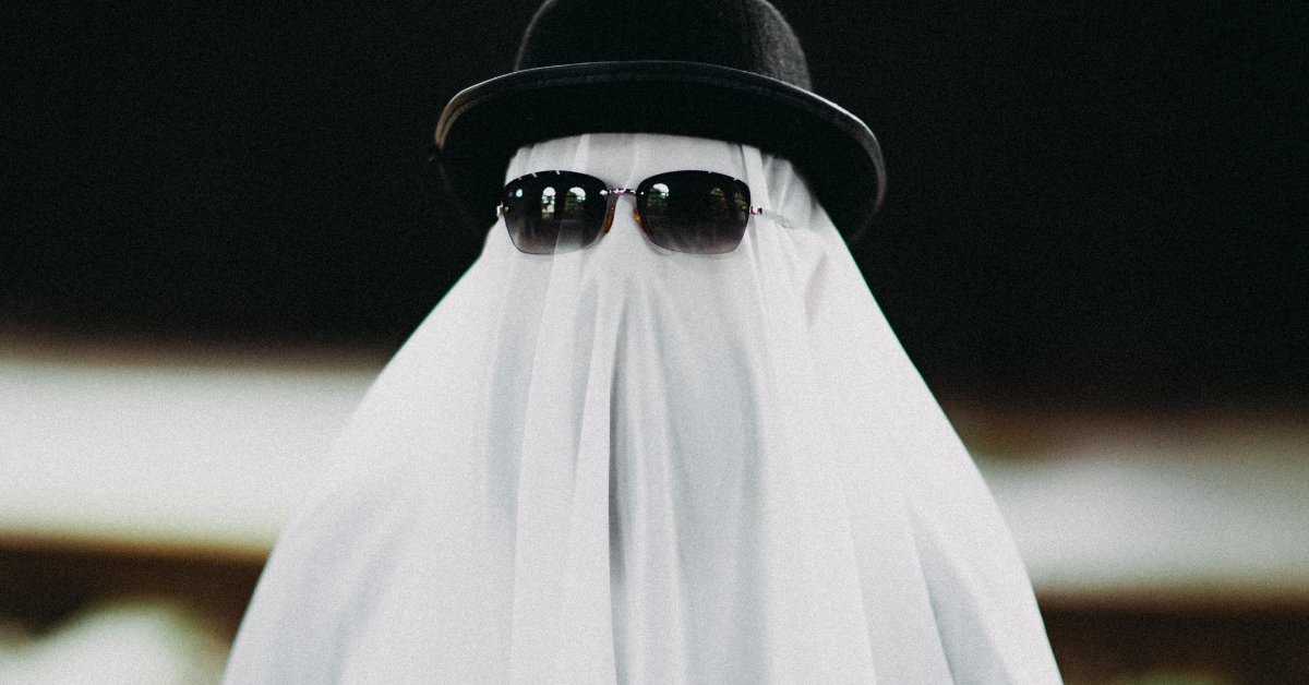 Kid dressed as a ghost wearing sunglasses